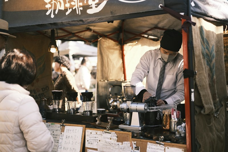 京都街边咖啡摊里，店主为客人磨豆，柜台摆着手写菜单